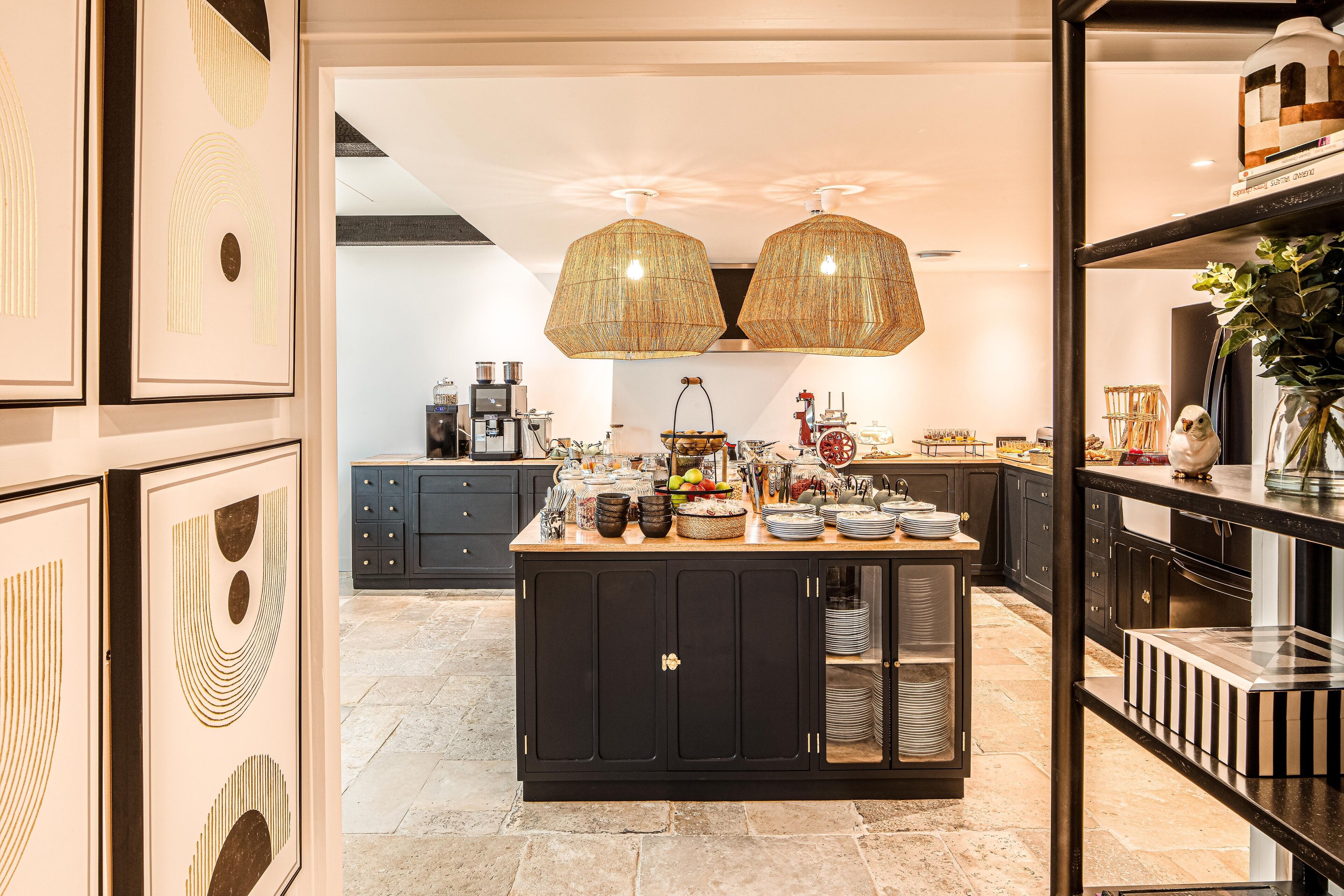 A modern kitchen with a central island, black cabinets, and a decorative ceiling light fixture.