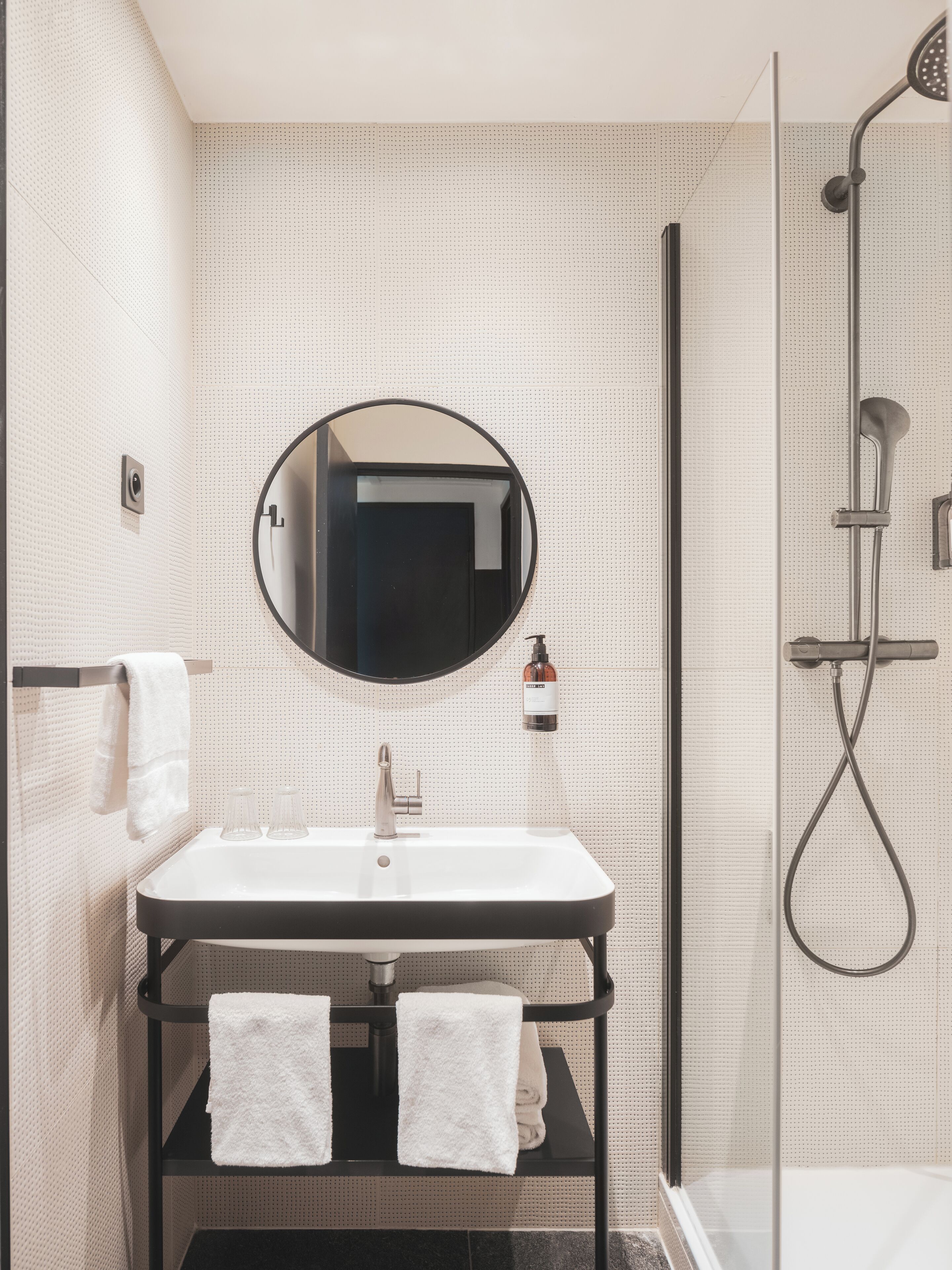 Un bagno con uno specchio rotondo, un lavandino e una doccia.