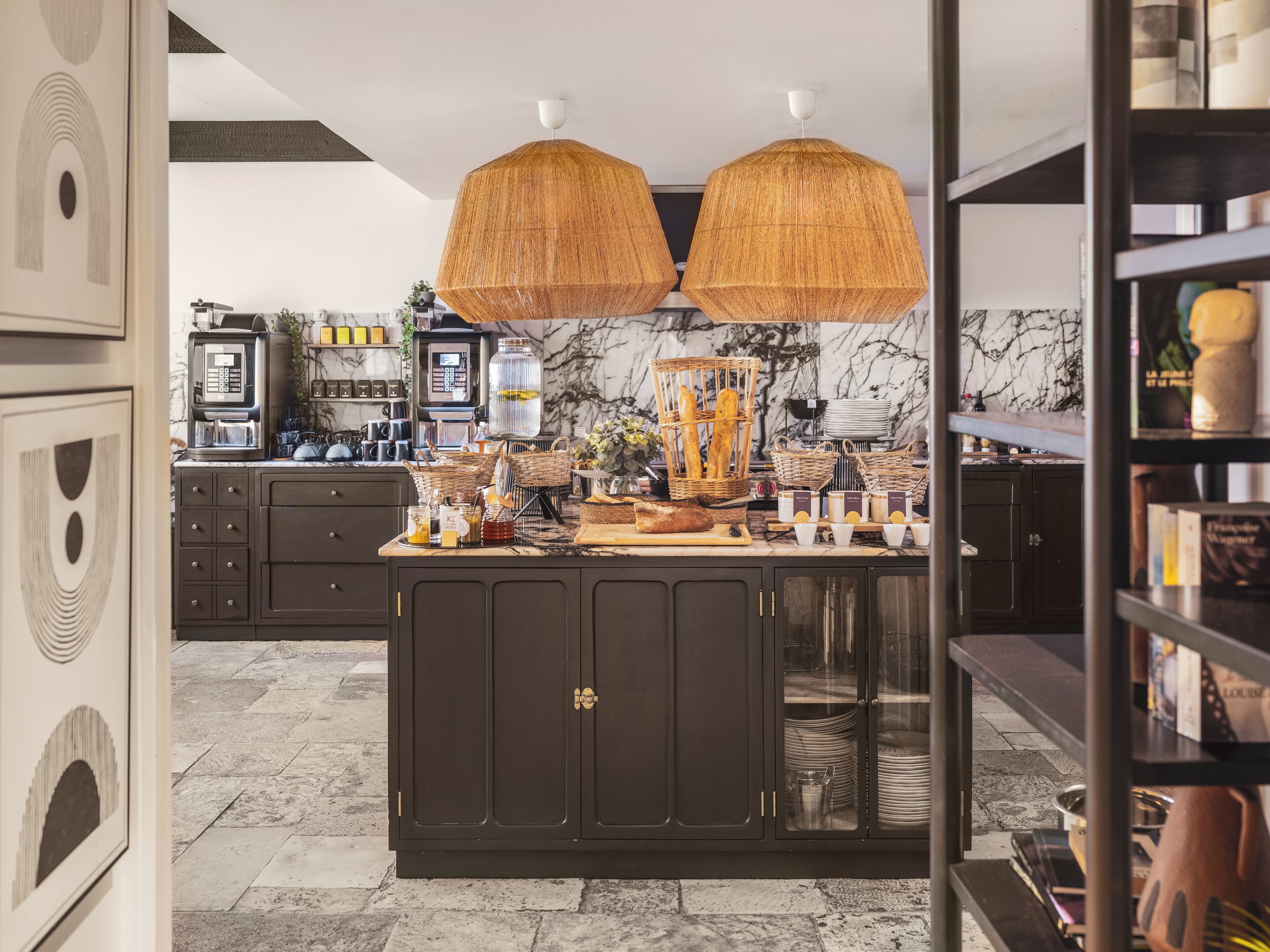 Una cocina moderna con armarios oscuros, salpicadero de mármol y una isla central con cestas y utensilios de cocina.