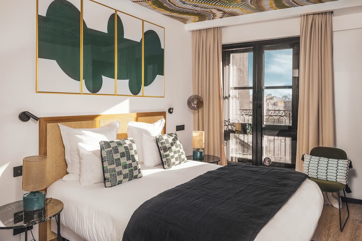 Habitación de hotel con una cama grande, vistas de la ciudad y un techo de diseño único.