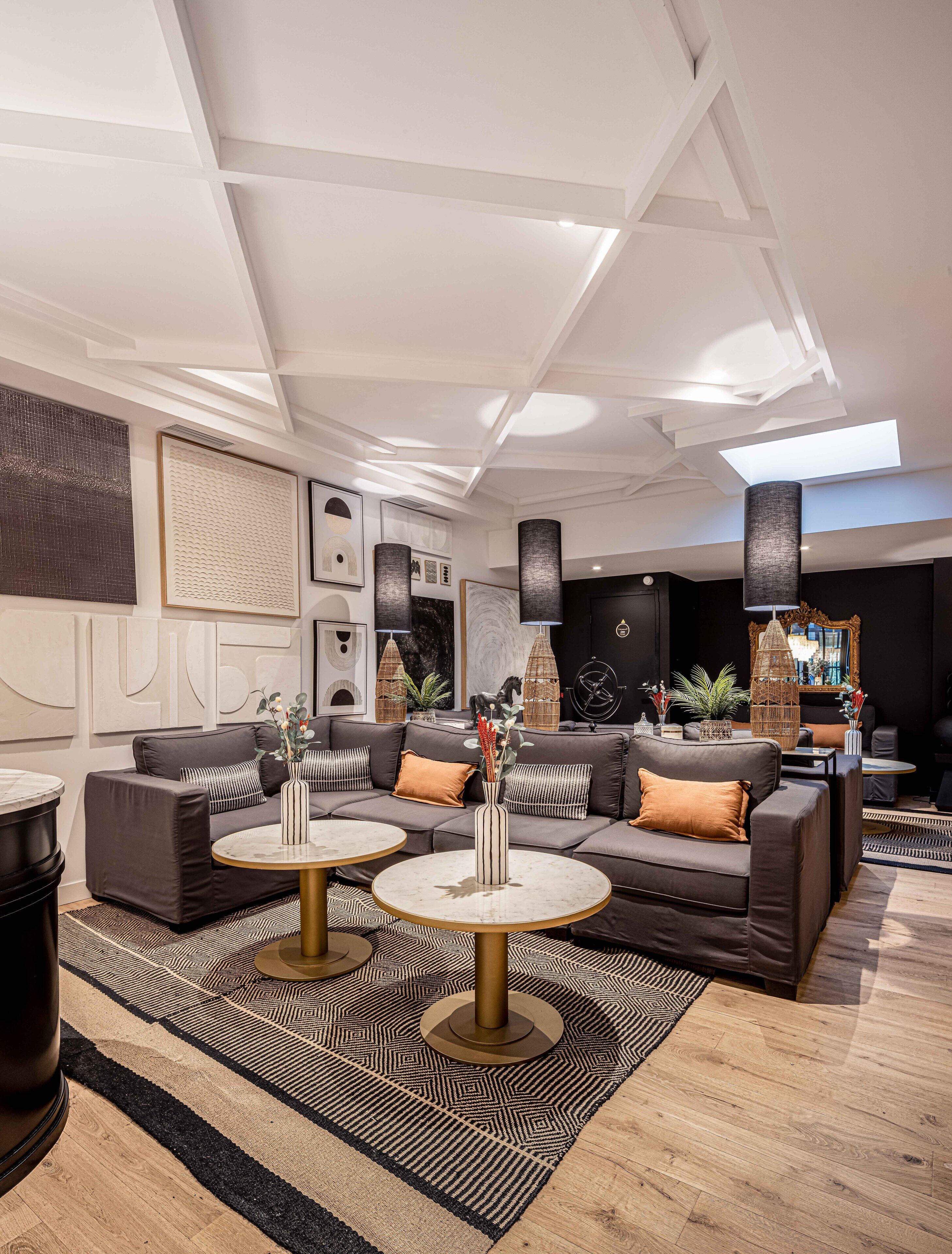 A modern living room with a sectional sofa, two round tables, and decorative vases.