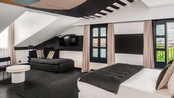 Un dormitorio moderno con una cama grande, un sofá, un televisor y vistas al balcón.