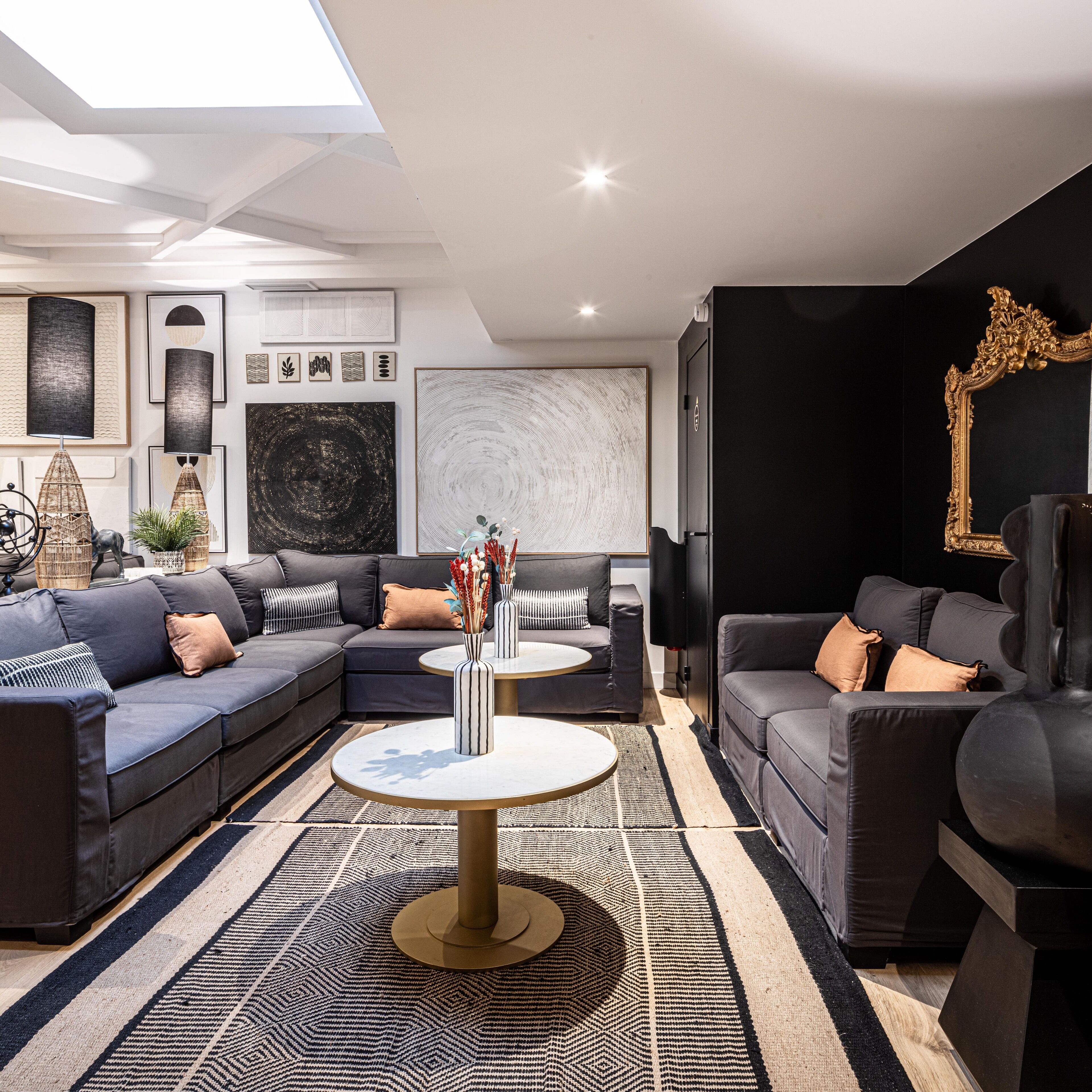 A modern living room with a sectional sofa, a round coffee table, and a large abstract painting on the wall.