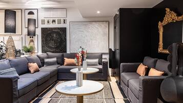 A modern living room with a sectional sofa, a round coffee table, and a large abstract painting on the wall.