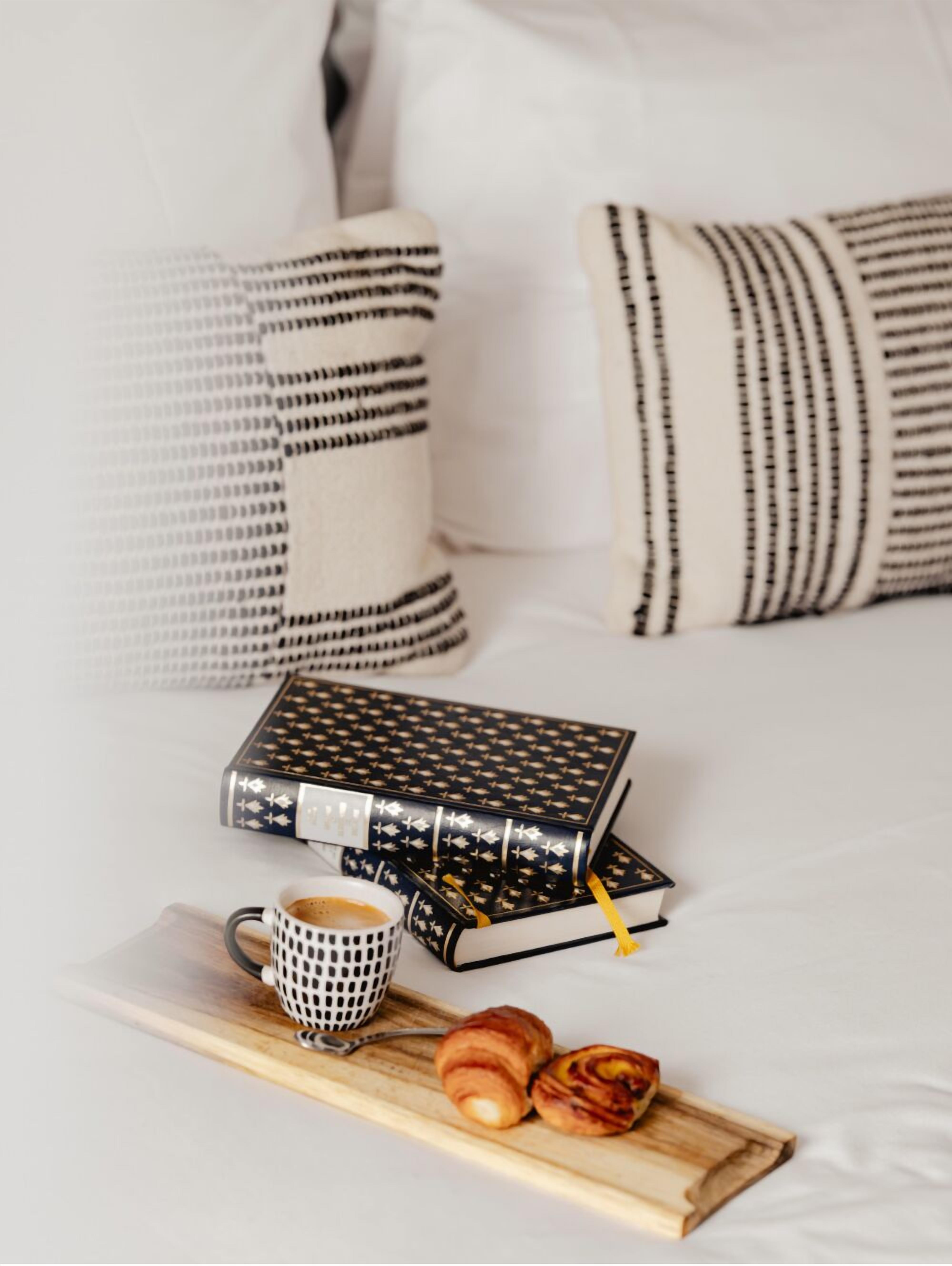 A neatly arranged breakfast setup with a coffee cup, pastries, and books on a tray.