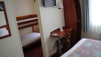 Una habitación de hotel con una cama litera, un escritorio con silla, un televisor y un armario.