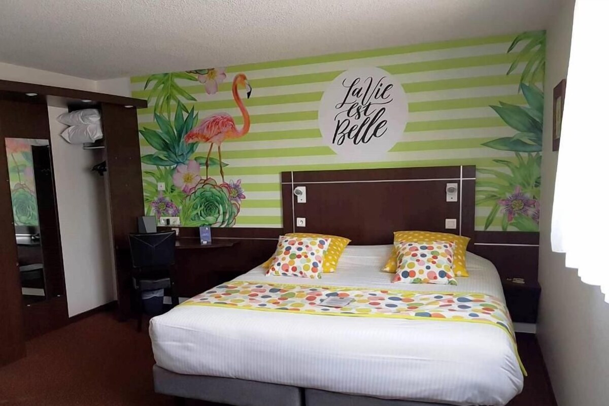 A hotel room with a bed, a nightstand, a desk, and a mirror.