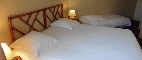 Una cama doble con sábanas blancas y dos lámparas de noche.