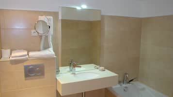Une salle de bain avec un lavabo blanc, un miroir, un porte-serviettes et une baignoire.