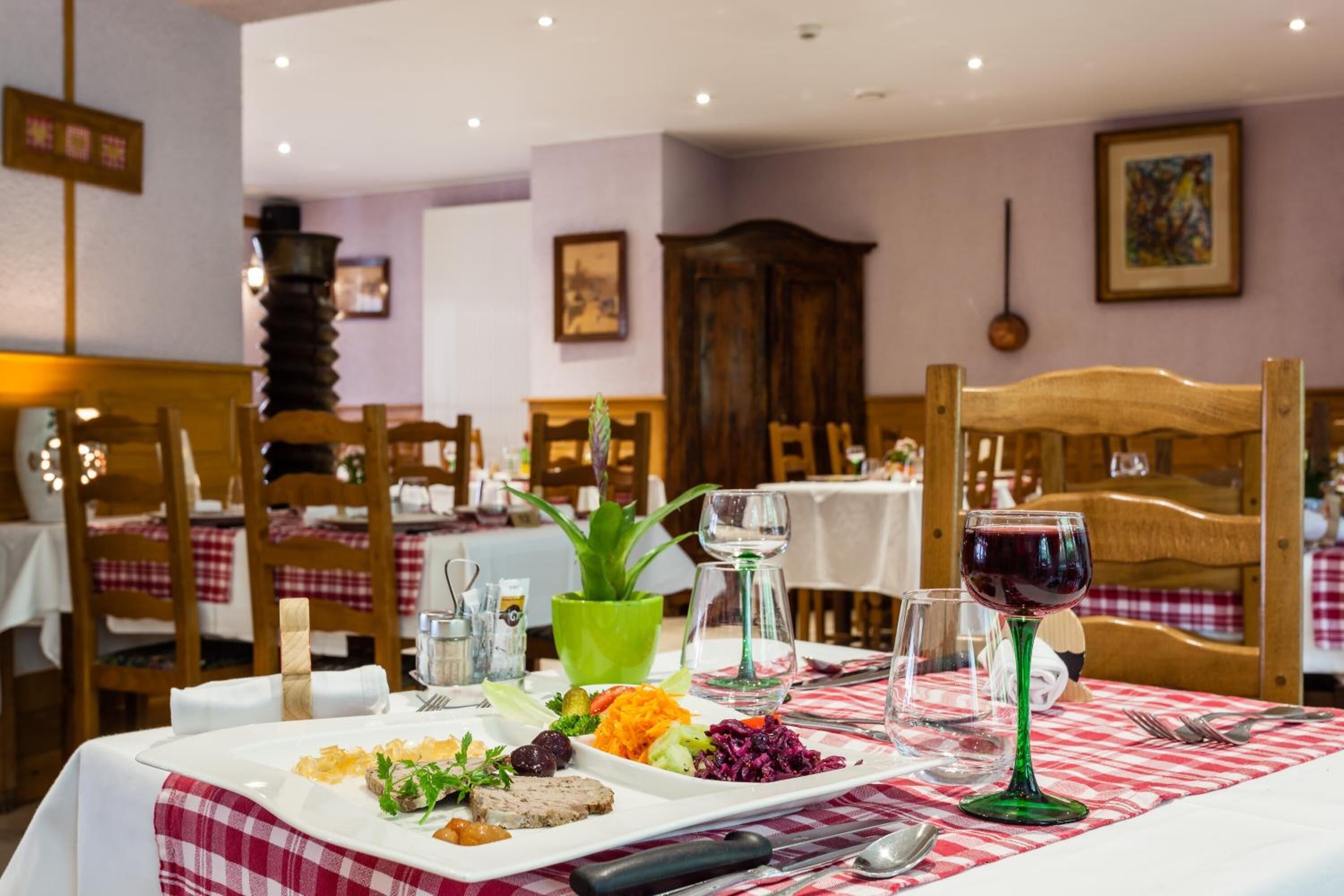 Una mesa de comedor lista con una variedad de platos, copas de vino y cubiertos.