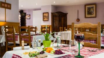 Una mesa de comedor lista con una variedad de platos, copas de vino y cubiertos.