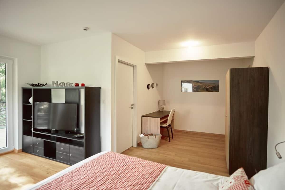 A bedroom with a bed, a TV, a desk, and a chair.