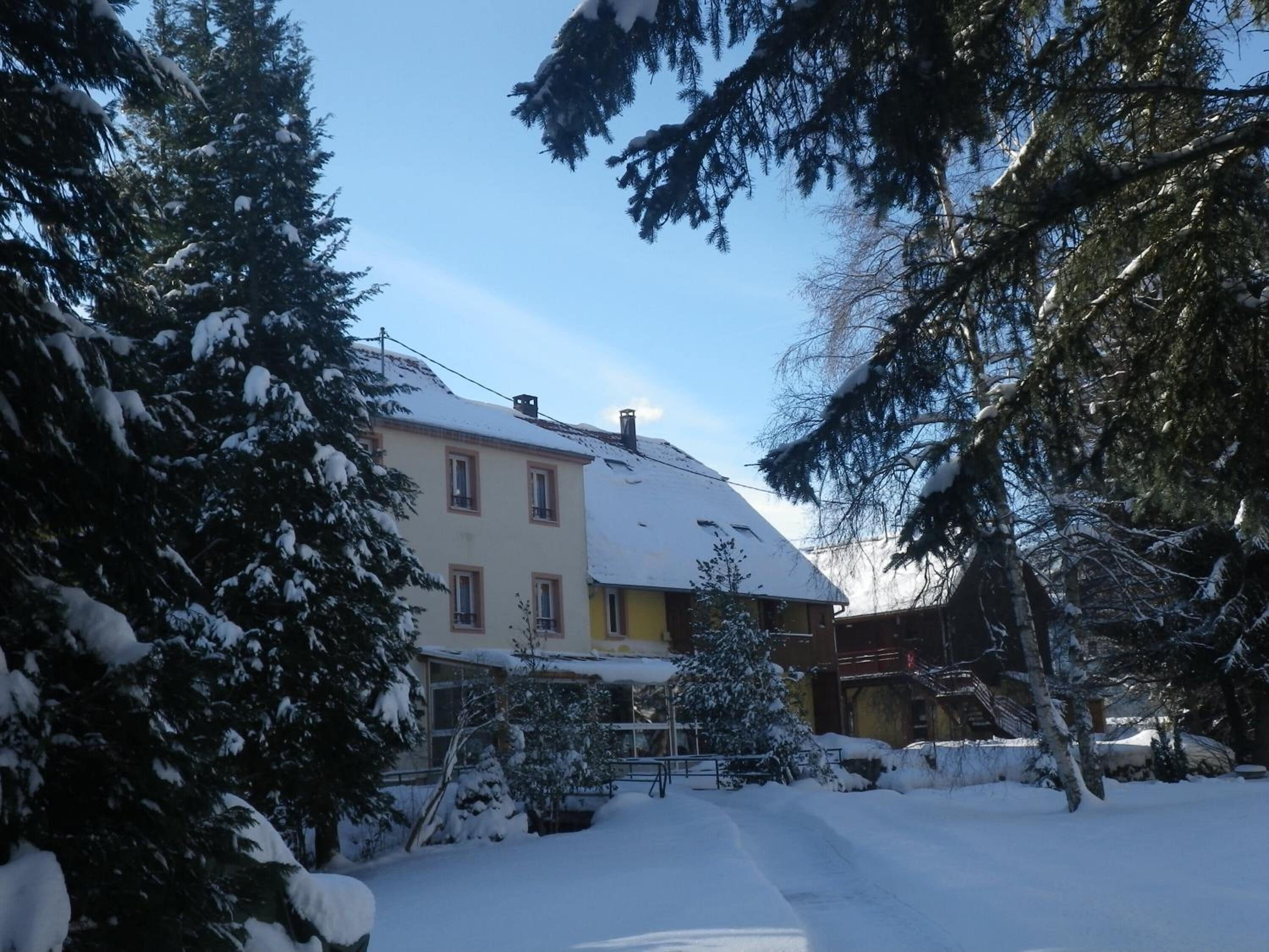 A two-story building with a snow-covered roof and surrounding trees.