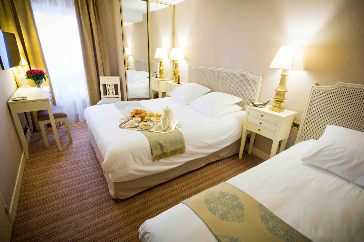 Hotellihuone, jossa on suuri sänky, yöpöydät, työpöytä ja peili.