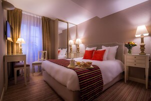 A hotel room with a large bed, bedside tables with lamps, a desk with a chair, and a large mirror.