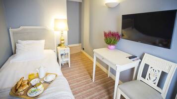 Une chambre d’hôtel équipée d’un lit, d’une table de chevet, d’une chaise, d’une télévision et d’un plateau de petit-déjeuner.
