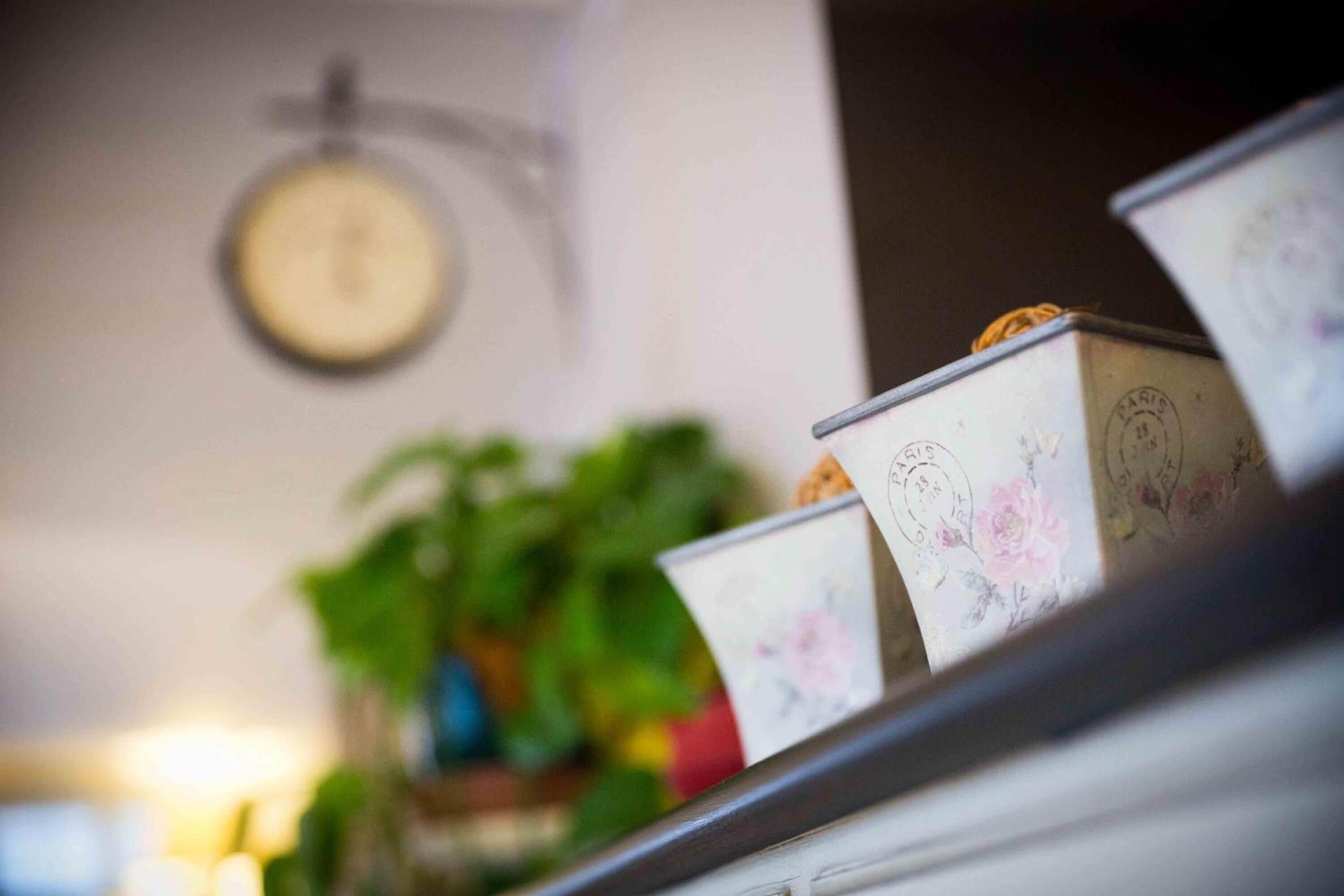 Una estantería con cajas decorativas y un reloj en la pared.