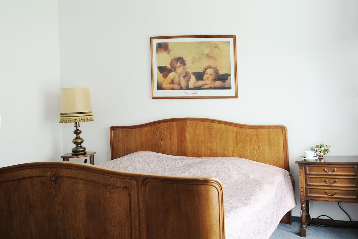 Ein Schlafzimmer mit einem hölzernen Bett, einem Nachttisch mit Lampe und einem gerahmten Bild an der Wand.