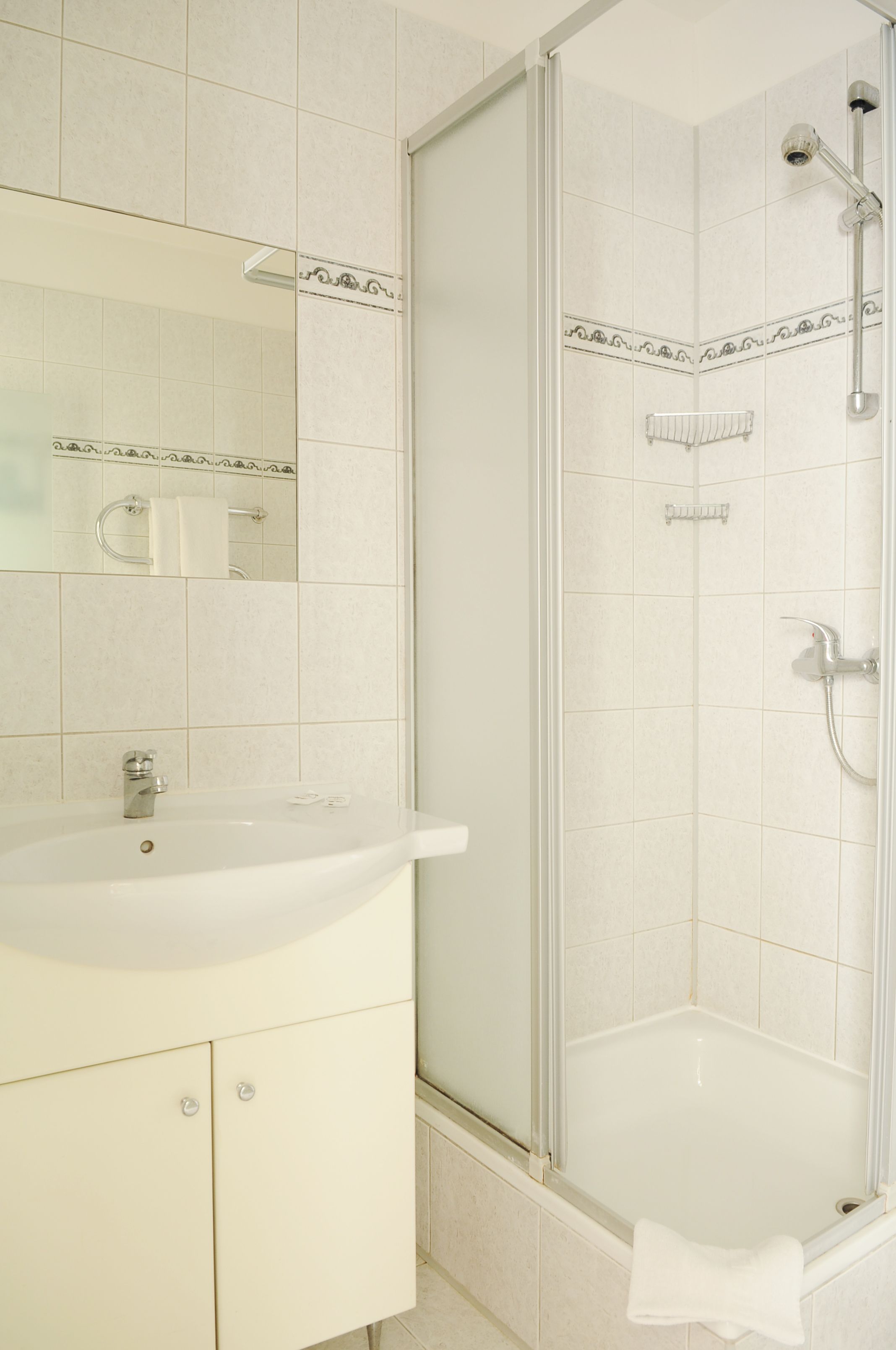 Ein Badezimmer mit einem weißen Waschbecken, Spiegel und Dusche.