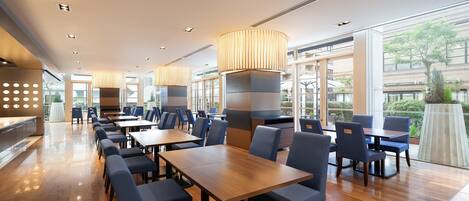 Un restaurante espacioso con techos altos, luminarias modernas y ventanas amplias que ofrecen vistas al exterior.