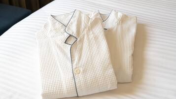 Ropa de cama blanca impecablemente doblada, con detalles de botones y una almohada.