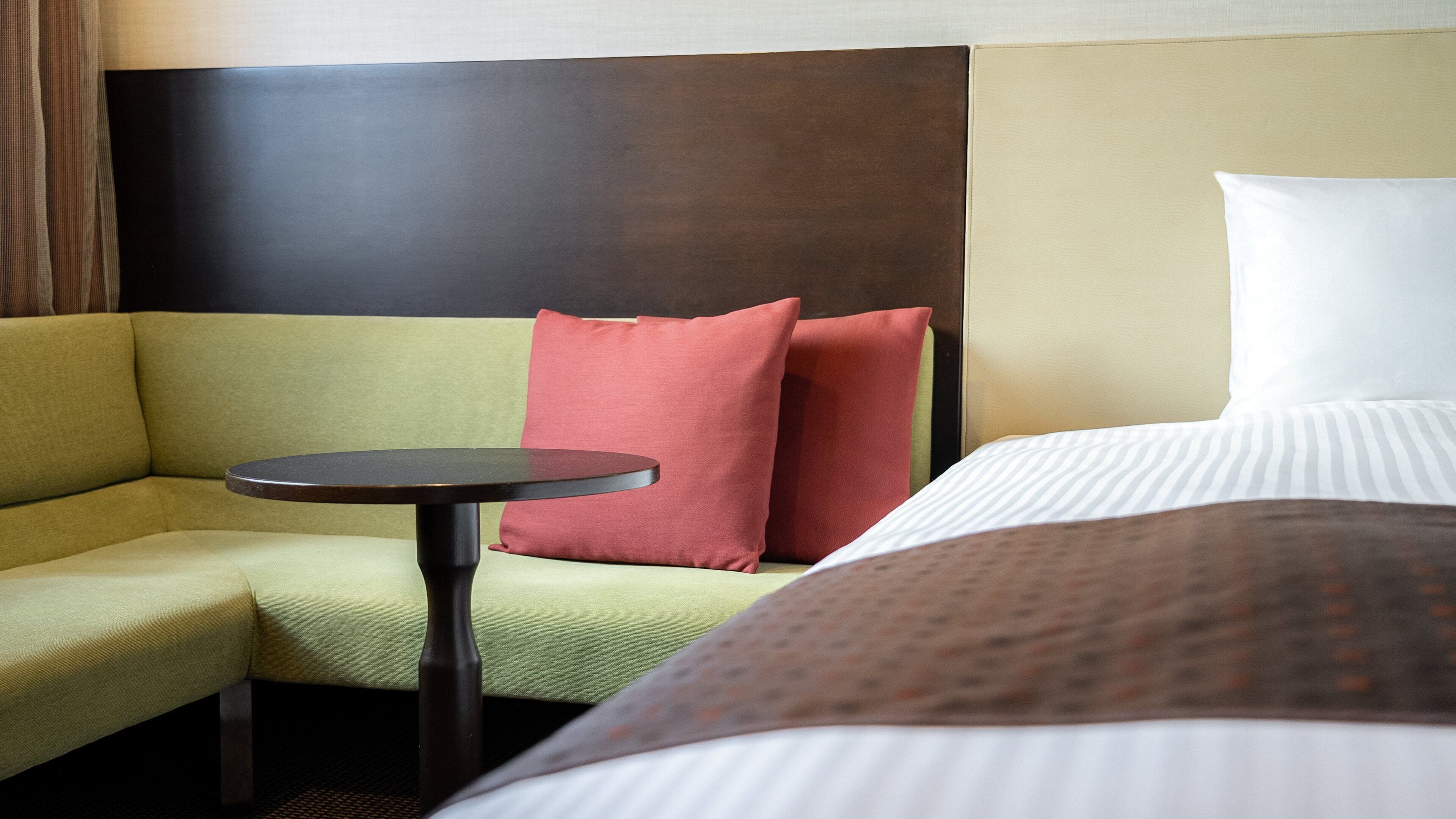 A hotel room with a bed, a sofa, and a small table.