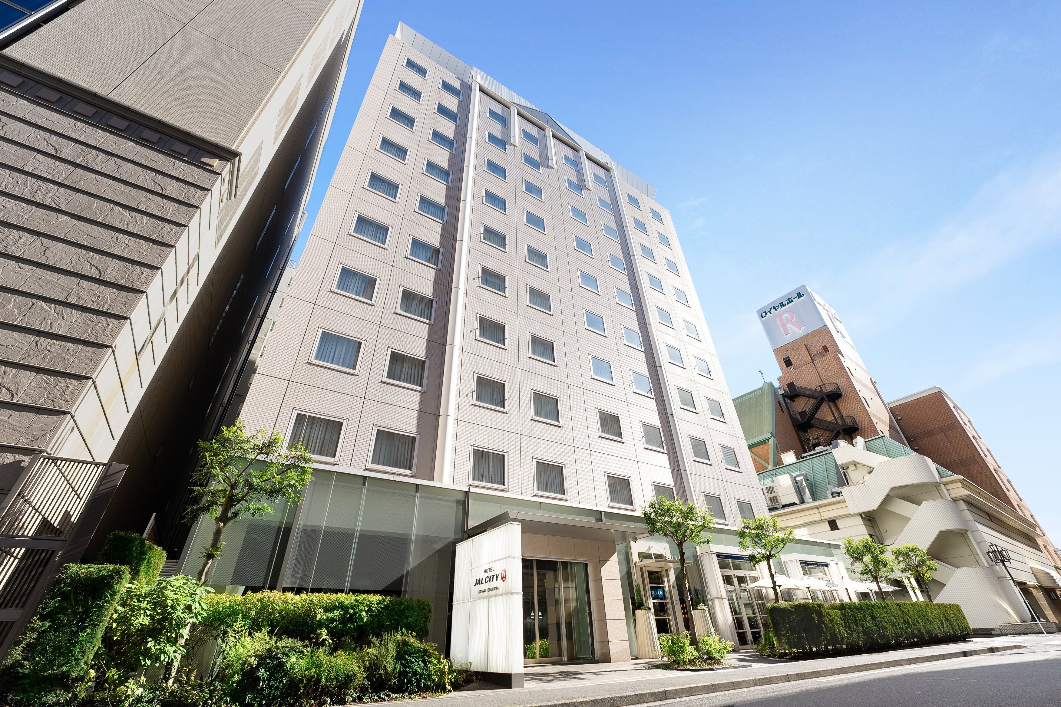 Un edificio hotelero moderno con varios pisos, ventanas amplias y una entrada destacada.