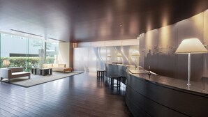 A modern interior with a curved reception desk, seating area, and large windows offering views of greenery. - Hotel JAL City Kannai Yokohama (Yokohama)
