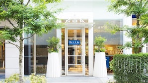 A modern building with a glass entrance, a sign reading "Silk," and a well-maintained garden area with trees and shrubs. - Hotel JAL City Kannai Yokohama (Yokohama)