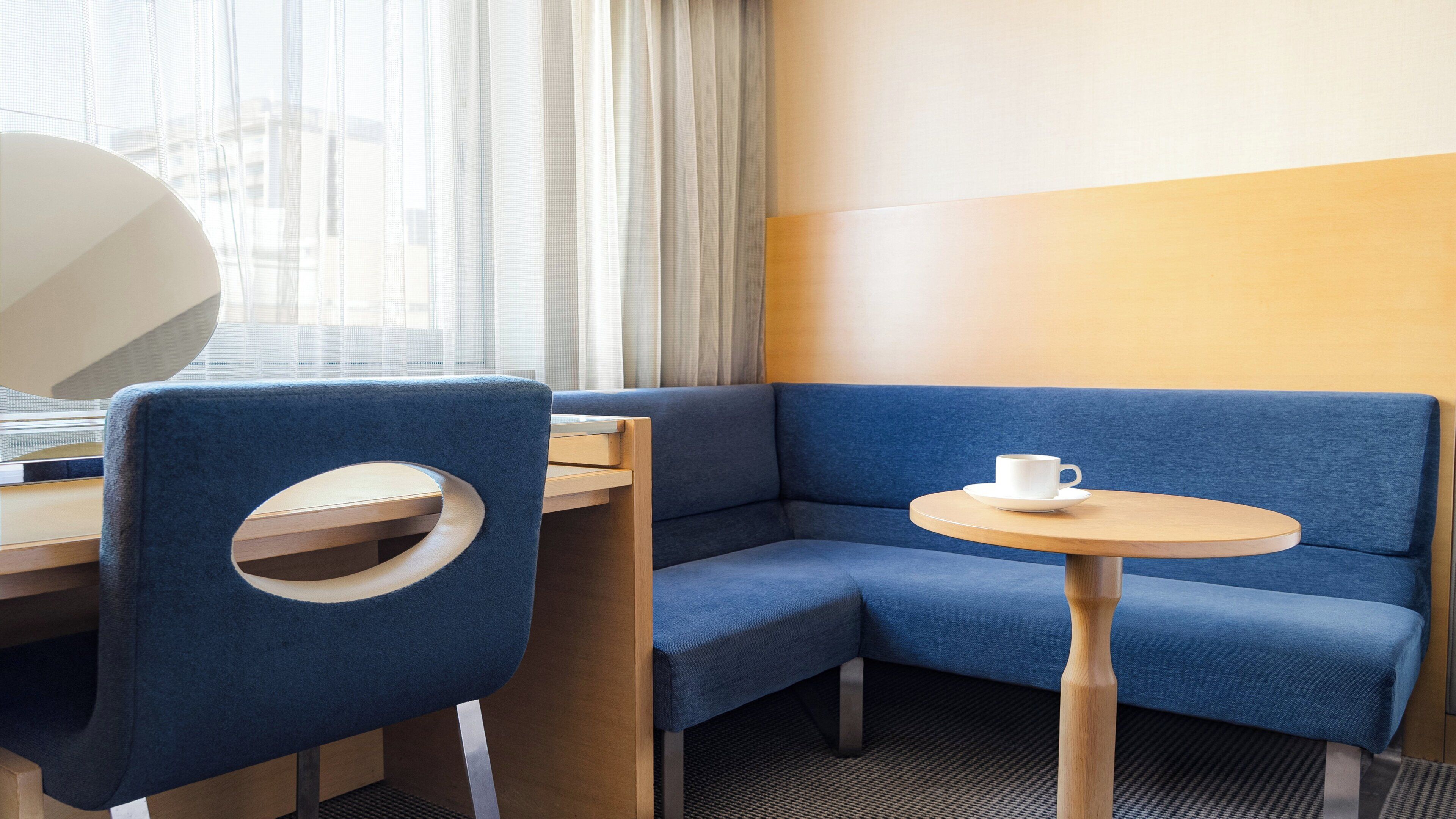 A corner seating area with a blue sofa, a small round table, and a white cup.