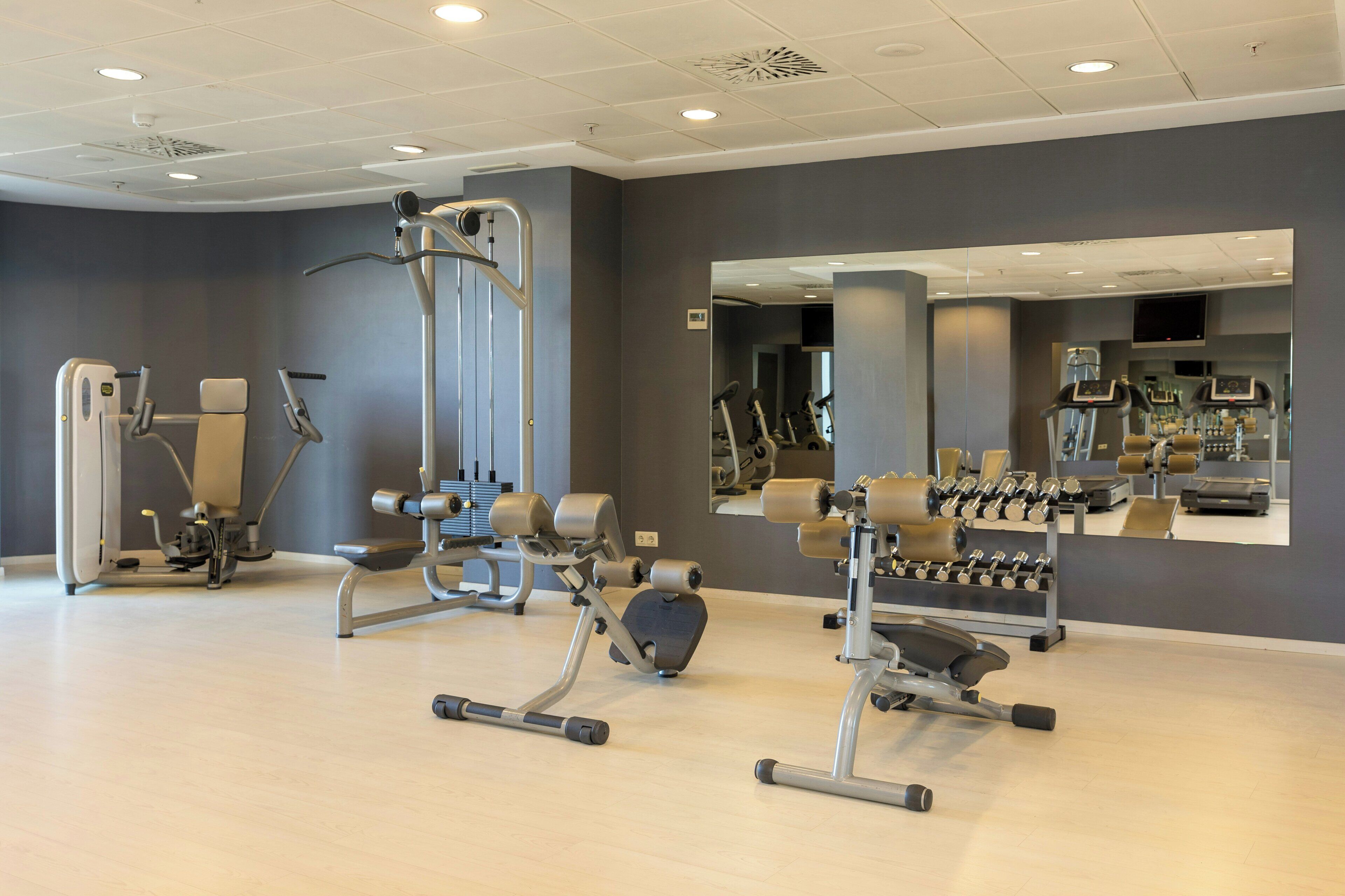 A gym with exercise equipment, a mirror, and a wall-mounted TV.