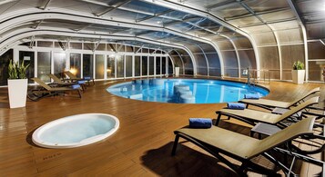 Una piscina techada, una piscina al aire libre, sombrillas