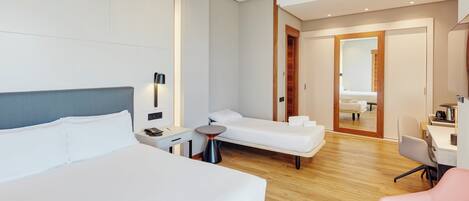 Une chambre d’hôtel comprenant un lit, une table de chevet, une lampe et un petit coin salon.