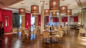 A spacious indoor area with multiple tables and chairs, large hanging pendant lights, and a red and white color scheme. - Sercotel Sorolla Palace Hotel (Valencia)