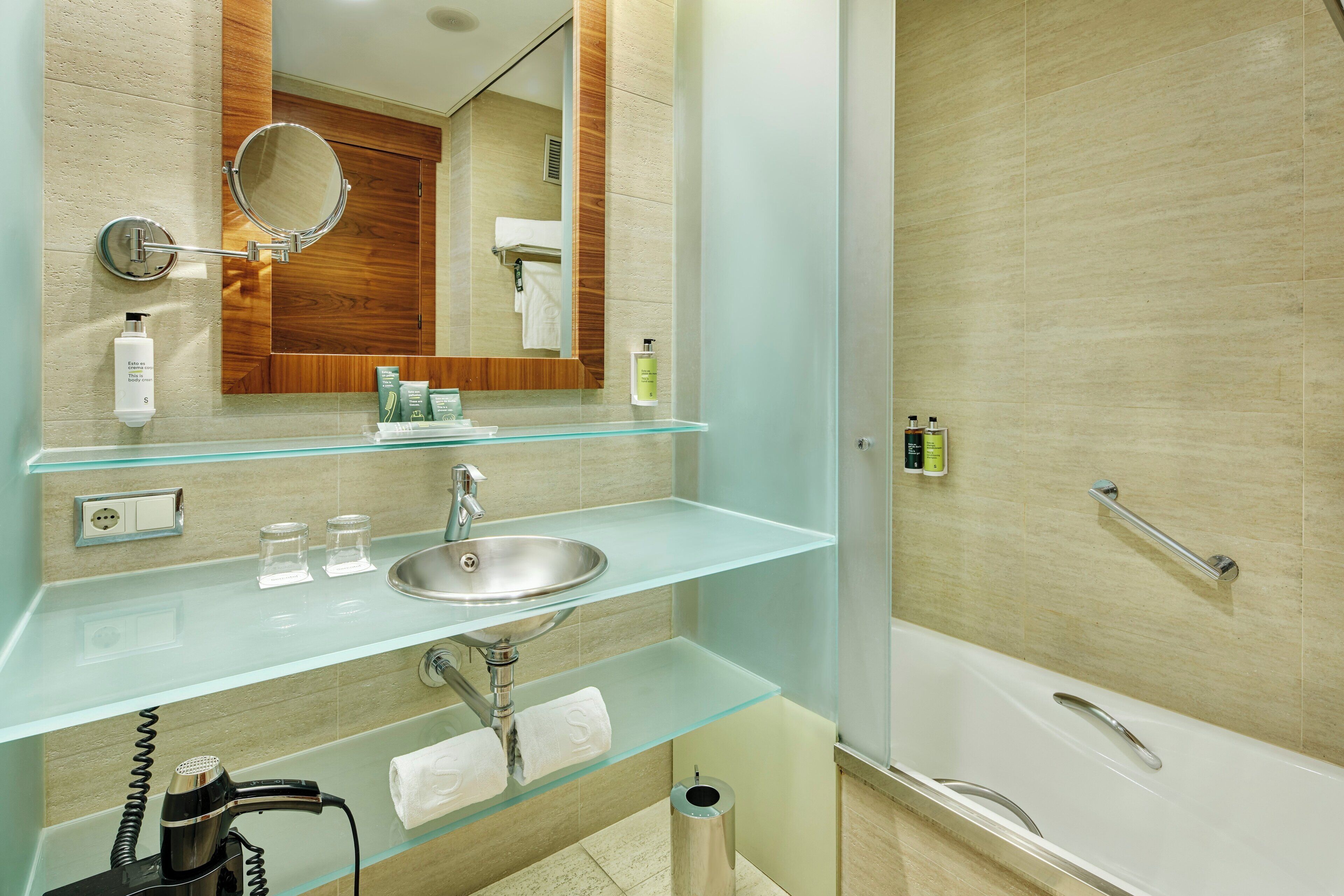 Un baño moderno con un lavabo de vidrio, un espejo, una ducha y un inodoro.