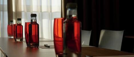 A conference table with several bottles and glasses, a pen, and a smartphone.