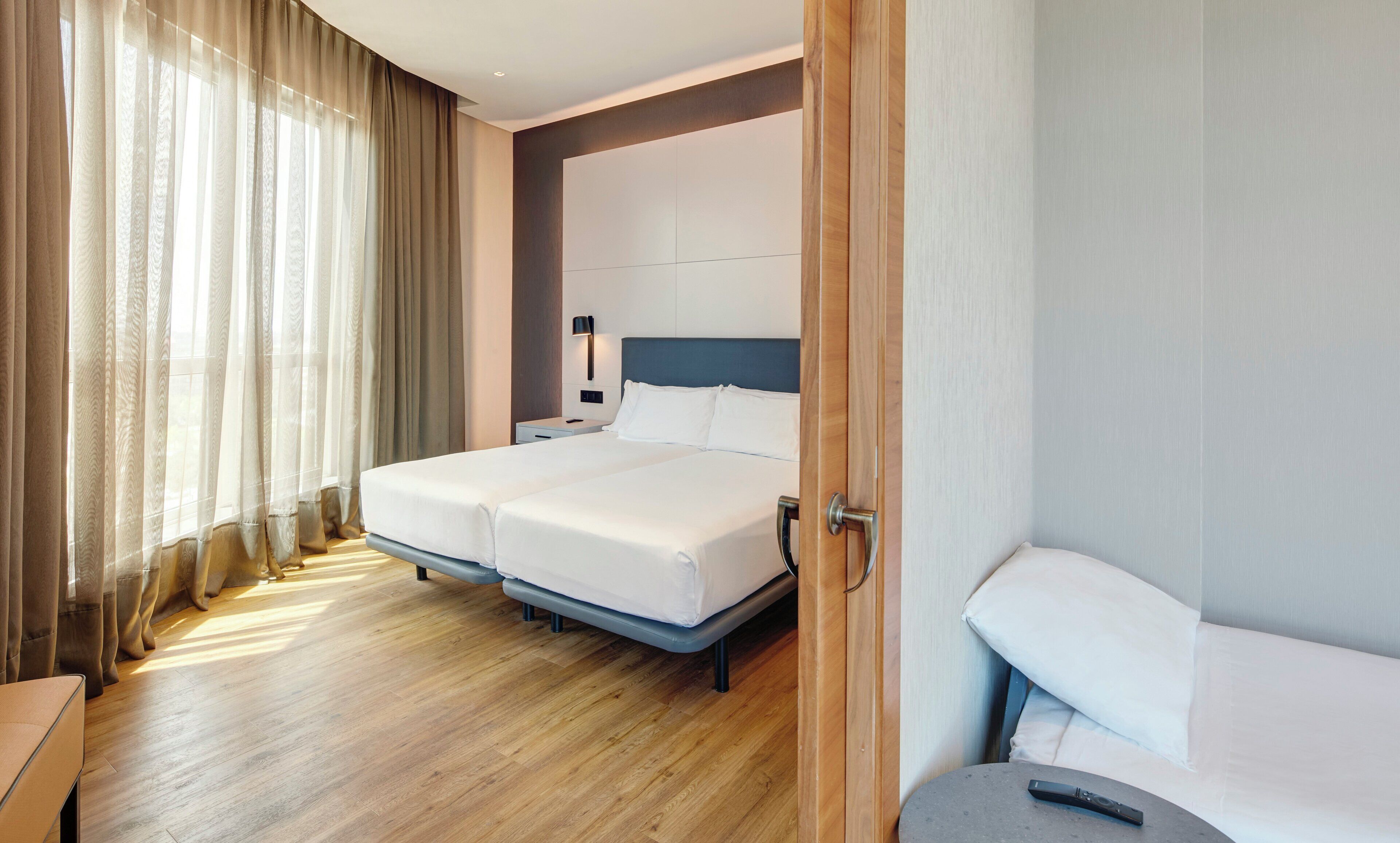 Una habitación de hotel con una cama doble, mesitas de noche, una lámpara y suelo de madera.