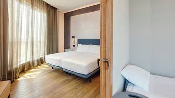 Una habitación de hotel con una cama doble, mesitas de noche, una lámpara y suelo de madera.