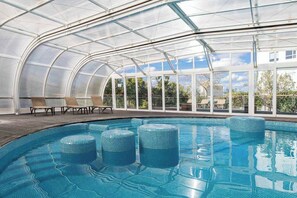 Una piscina techada, una piscina al aire libre, sombrillas