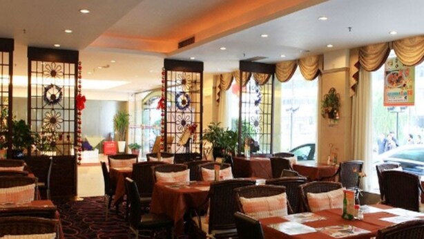 Un restaurante con sillas y mesas de mimbre, ventanas amplias y detalles decorativos como coronas y carteles.