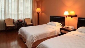 Habitación de hotel con dos camas, un escritorio, una silla y una lámpara.