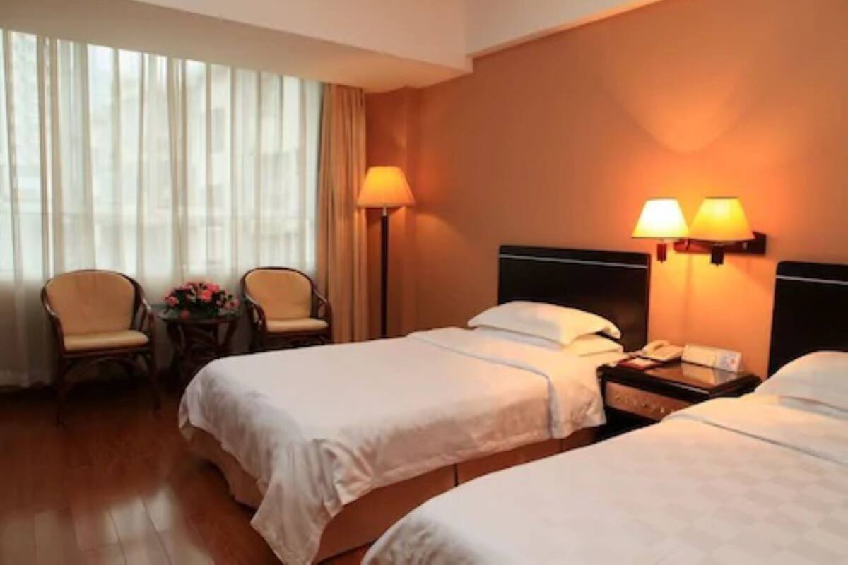 Habitación de hotel con dos camas, un escritorio, una silla y una lámpara.