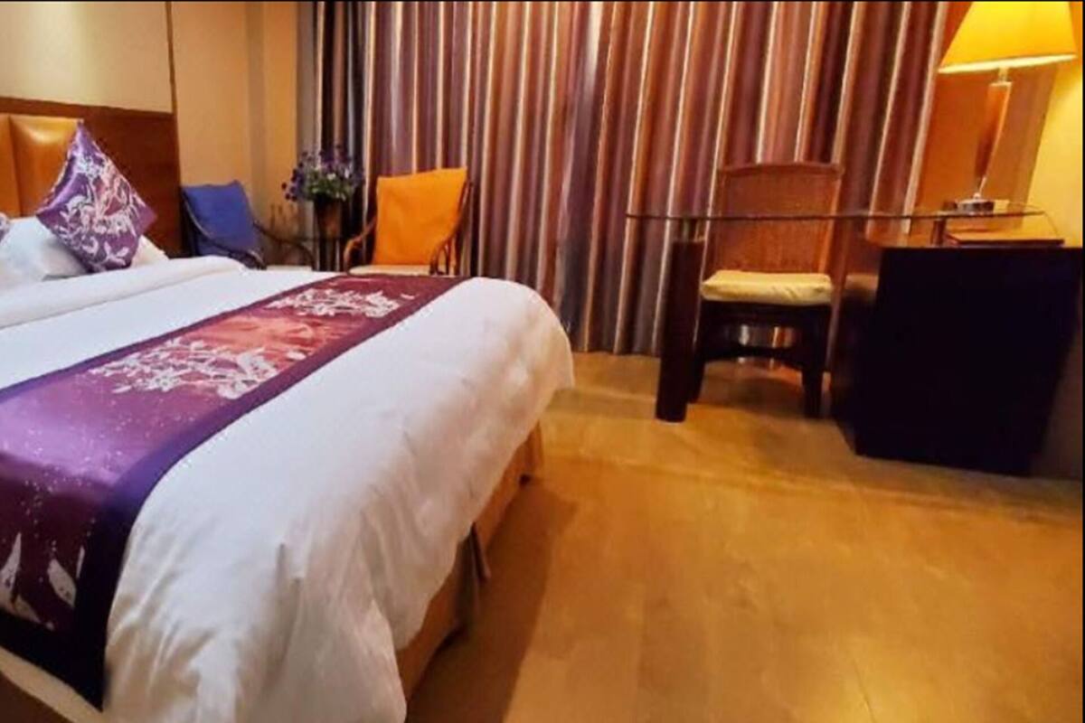 Una habitación de hotel con una cama grande, una mesita de noche, un escritorio y una silla.