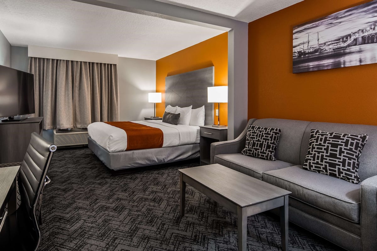 A hotel room with a bed, a sofa, a table, and a desk.