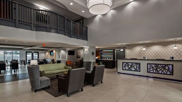 Una hall moderna con reception, area salotto e una scala che conduce a un piano superiore.