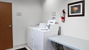 A laundry room with a washing machine, dryer, and a fire extinguisher on the wall.