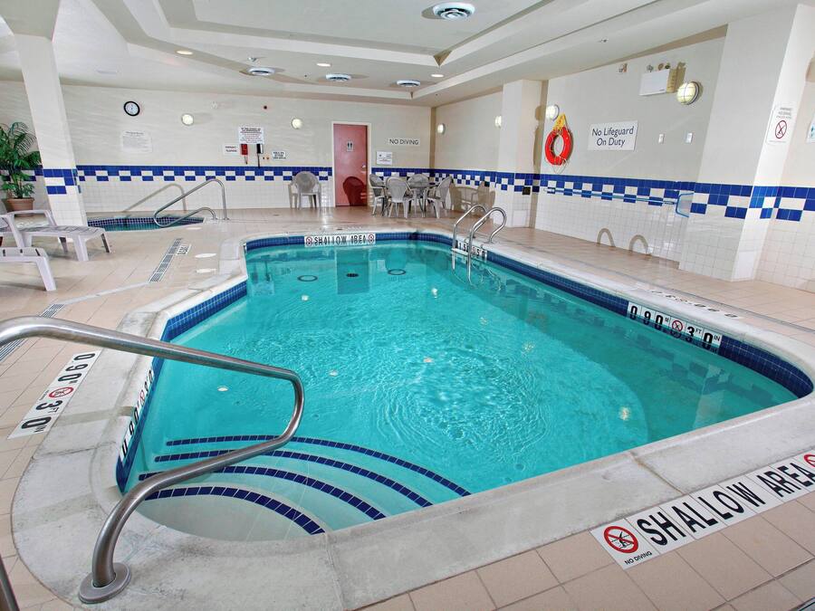 An indoor swimming pool with a shallow area, a lifeguard chair, and a no diving sign.