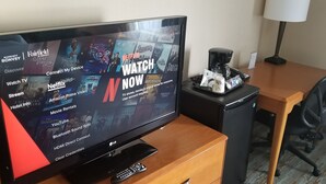 A hotel room with a TV displaying various streaming services and a coffee maker on a table. - Fairfield Inn & Suites by Marriott Sudbury (Sudbury)