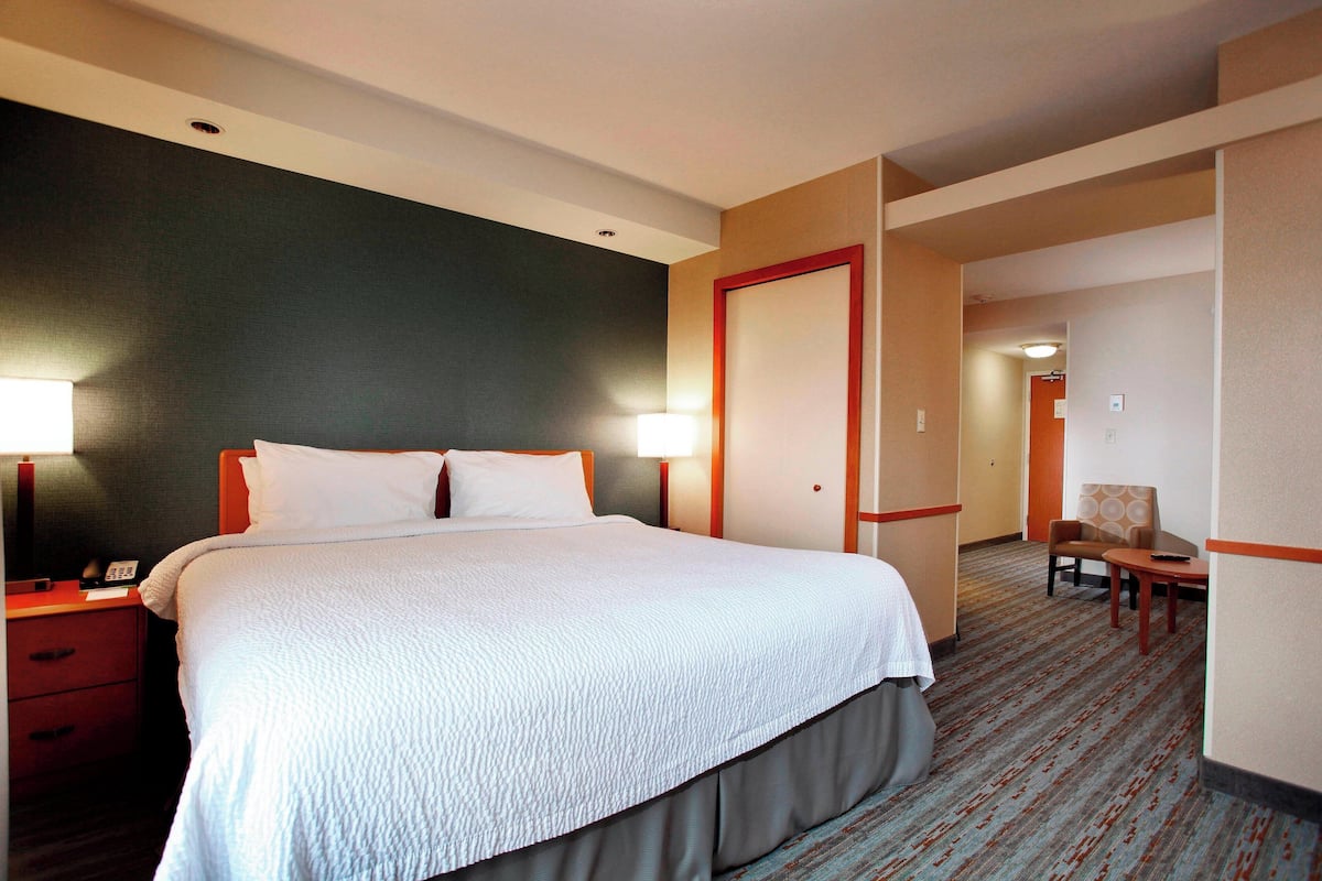 Een hotelkamer met een groot bed, nachtkastjes, een stoel en een bureau.