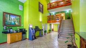 A brightly colored lobby with a reception desk, ATM, and a staircase leading to an upper level. - Quality Inn & Suites near Six Flags East (Atlanta)